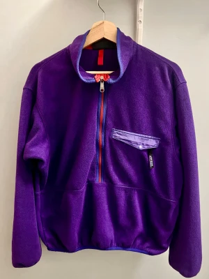 Sällsynt vintage Patagonia fleece  - Patagonia Fleece - Made in USA (Dam, Strl. S) Snygg och tidslös i en strålande lilla färg. Tillverkad i USA, vilket gör den extra eftertraktad bland retro entusiaster. Trots åldern är tröjan väldigt omhändertagen. Mjuk, varm och perfekt för både vardag och friluftsliv. Missa inte chansen! 