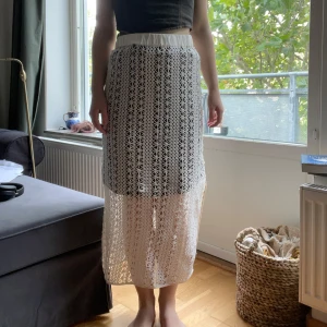 Vit långkjol i spets från Résumé - Nyskick och aldrig använd! Supersnygg vit långkjol från Résumé med elastisk midja och vackert virkad spets. Kjolen har ett innerfoder och ett genombrutet mönster som ger en luftig och somrig vibe.