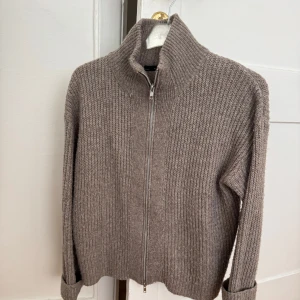 Beige stickad kofta från 157 - Mysig beige stickad kofta från 157 med hög krage och hel dragkedja framtill. 