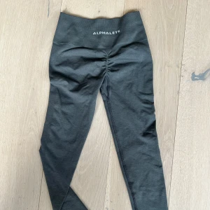 Mörkgrå leggings från Alphalete XS - Snygga mörkgrå leggings från Alphalete i storlek XS. De har hög midja och en tight passform som framhäver figuren. Perfekta för träning eller chill dagar. Materialet är stretchigt och mjukt för maximal komfort. Som nya