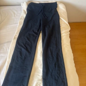 Svarta mjukisbyxor med snörning XS - Svarta mjukisbyxor från 157 i storlek XS. Byxorna har en bred resår i midjan med snörning och raka ben. Tillverkade i mjukt bomullsmaterial som är skönt att ha på sig. Perfekta för chill eller träning.