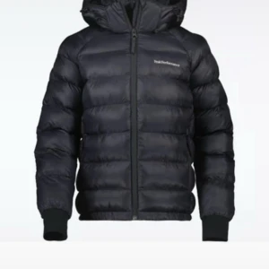 Svart dunjacka Peak Performance L - Säljer en svart dunjacka från Peak Performance i storlek L. Jackan har huva, dragkedja framtill och ribbade muddar vid ärmslut. Klassisk pufferstil med diskret logga på bröstet. Perfekt för kalla dagar och riktigt skön att bära. Oanvänd köpt för 4200 säljer för 1500 för att den har legat i min garderob i typ ett år