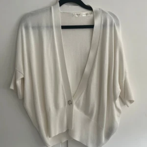 Vit kofta från InWear med kort ärm - Superfin vit kofta från InWear med djup v-ringning och en knapp framtill. Modellen är loose fit med korta ärmar och mjukt, tunt stickat material. 