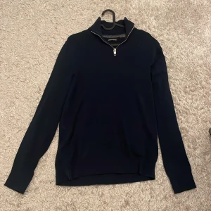Mörkblå half zip-tröja Jack & Jones - Mörkblå långärmad tröja från Jack & Jones med stilren half zip-dragkedja i halsen. Tröjan har en klassisk passform och är tillverkad i mjukt material som passar perfekt till lager-på-lager. Enkel och snygg design utan mönster.
