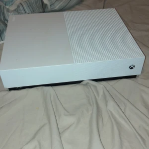 Xbox One S - Xbox One S i vitt utförande. Konsolen är i gott skick med endast mindre ytliga märken synliga på ovansidan. Perfekt för gaming, streaming och underhållning. Strömkabel och handkontroll ingår ej på bilden.
