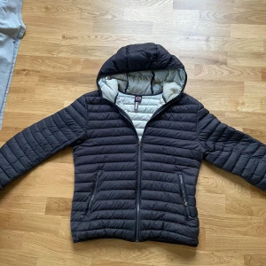 Svart pufferjacka från Colmar - Säljer en svart pufferjacka från Colmar med huva och dragkedja framtill. Jackan har två fickor med dragkedja och en ljus insida. Perfekt för kyliga dagar och riktigt snygg till jeans eller joggers.