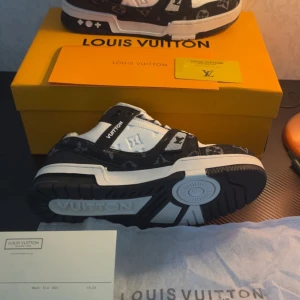  svartvita sneakers - helt ny och onandvända skor storlek 42 kommer med allt på bilden. Snygga sneakers i svart och vitt med klassiskt monogrammönster. Skorna har rund tå, platt sula och tydliga detaljer på sidan och plösen. Tillverkade i en mix av skinn och textil med vita snören och kontrasterande svarta partier. Perfekta för dig som gillar lyxig streetstyle. INTE RIKTIG