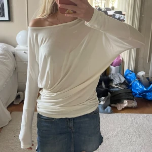 Vit offshoulder långärmad topp - Säljer en vit långärmad topp man både kan ha ”en axel ute” eller som en boatneck och sen har den draperad midja. Tunt, mjukt och såå skönt material som faller snyggt och ger en chill men ändå stilren vibe 🥰🥰