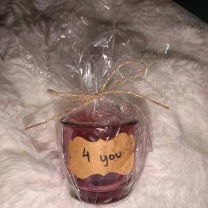 Ljuslykta med ett ljus i - Bilderna visar en liten rosa glaslykta, inslagen i cellofan med snöre och etikett '4 you'. Produkten är från Rusta, enligt etiketten under. Inga synliga defekter eller slitage, ser oanvänd ut. Perfekt som present eller dekoration.