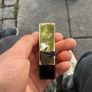 YSL Rouge Pur Couture P22 Läppstift - Säljer ett lyxigt YSL Rouge Pur Couture läppstift i färgen P22, en intensiv och cool rosa nyans. Hylsan är elegant i guld och svart med YSL-loggan i svart metall. Läppstiftet har klassisk form och känns riktigt glam i handen.