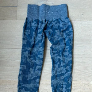 NVGTN leggings - Säljer ett par blå camo-mönstrade leggings från NVGTN i storlek XS. Formar kroppen,  Perfekta för träning och riktigt snygga på gymmet.