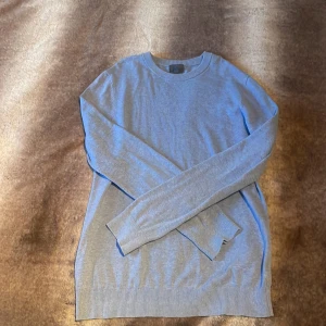 Ljusgrå slim fit stickad tröja H&M XS - En stilren ljusgrå stickad tröja från H&M i slim fit-modell. Tröjan har rund halsringning, långa ärmar och ribbade muddar vid ärmslut och nederkant. Perfekt för lager-på-lager och enkel att matcha med jeans