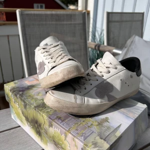 Skor från märket The Gallerist - Snygga vita sneakers från The Gallerist med svart hälparti och grå klöverdetalj på sidan, det är gamla designen så skorna finns inte längre i just denna modell. Perfekta för dig som gillar stilrena och trendiga sneakers med unika detaljer. Nypris 2200kr, Strl 41,  Skobox ingår. (Priset är inte fast) Hör av dig vid intresse/ frågor! 