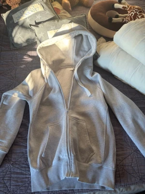 Russemerch zip.  Storlek L, passar mig som är 183 bra - Ljusgrå hoodie med dragkedja framtill, två stora fickor och justerbar huva med snören. Mjuk insida i fleeceliknande material som gör den extra skön. Perfekt för en avslappnad och stilren look.