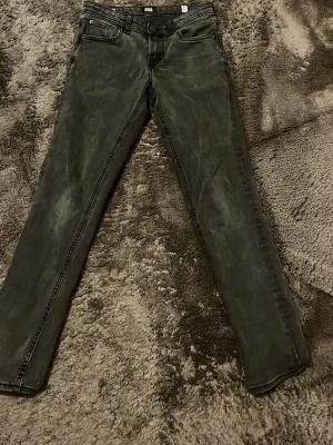 Svarta skinny jeans från Jack & Jones - Säljer ett par svarta skinny jeans från Jack & Jones med klassisk femficksdesign och diskret tvättad look. Jeansen har normal midja och smal passform hela vägen ner. Perfekta till en avslappnad streetstyle eller när du vill ha en clean look. Sitter som W27-28 L28, var inte rädd för att ställa frågor. Pris går att diskutera 