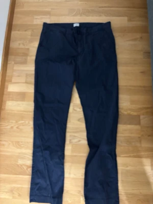 Mörkblå chinos från Route National - Snygga mörkblå chinos från Route National med klassisk rak passform. Tillverkade i mjuk bomull som känns skön mot huden. Perfekta för dig som vill ha en clean och stilren look. Bälteshällor och knappstängning i midjan.