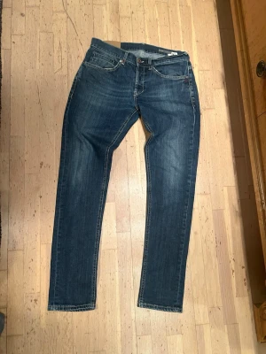 Dondup jeans George  - Snygga blå dondup  jeans med slim fit och klassisk femficksdesign. Jeansen har slitningar och kontrastsömmar, samt dondup logga på bakfickan. Passar dig som gillar en modern och smal siluett. Materialet är slitstarkt jeans i bomull. Storlek 33, passar 32,31