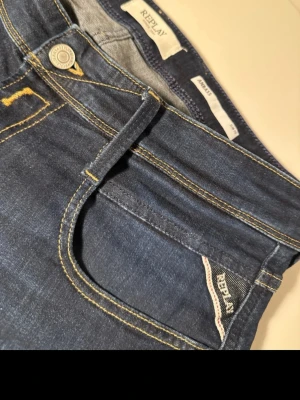 Replay Hyperflex Anbass jeans blå  - Snygga blå Replay Hyperflex Anbass jeans med klassisk femficksdesign och kontrastsömmar. Jeansen har en modern passform och är tillverkade i stretchigt jeansmaterial för extra komfort. Perfekta för dig som vill ha stilrena och bekväma jeans.