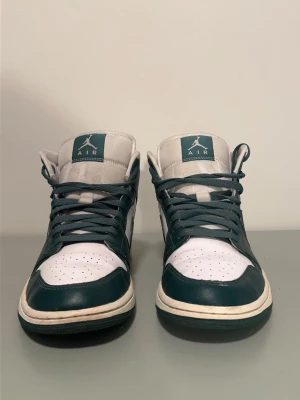Air Jordan 1 mid - Säljer ett par Air Jordan 1 Mid i grön och vit färg. Skorna är sparsamt använda och i fint skick. Inga större skador. Överdelen i läder är hel och fräsch, loggor och swoosh i bra skick. 100% äkta