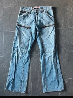 Ljusblå jeans med dragkedjor - Unika ljusblå jeans med flera dragkedjor framtill och coola detaljer. 