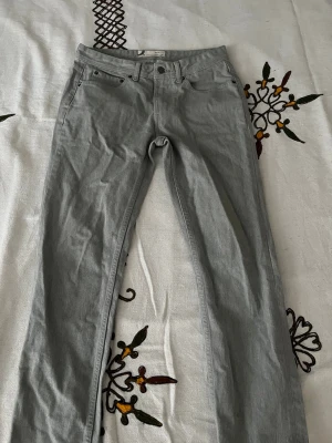Grå slim fit jeans från Dressman - Snygga grå slim fit jeans från Dressman med klassisk femficksmodell och bälteshällor. Jeansen har en rak passform med smal siluett och är tillverkade i mjuk bomullsdenim med lite stretch för extra komfort.