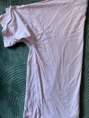 Ljusrosa t-shirt med tryck från Monki - T-shirt i rosa från Monki med coolt grafiskt tryck på bröstet där det står 'Find Your Fire' i metallicgrönt. Klassisk rund halsringning och korta ärmar. Perfekt för dig som vill ha en enkel men ändå statement vardagslook.