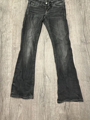 Svarta bootcut jeans med vita sömar från Gina Young  - Svarta Bootcut jeans från Gina Young. Grå/svarta med lite ljusare på knäna. Fickor på rumpan och har vita sömar. 