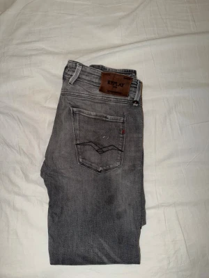 Grå Replay jeans straight fit - Snygga grå jeans från Replay med klassisk femficksmodell och raka ben. Jeansen har en mörkgrå tvätt, Replay-lapp bak i midjan och diskreta slitningar för en cool look. Tillverkade i mjuk bomullsdenim med en bekväm passform.