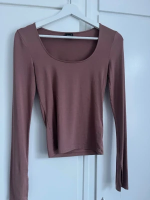 Ros långärmad topp - En enkel och stilren ljusbrun långärmad topp från Gina tricot. Modellen har en rund, djup ringning och är croppad i passformen. Tillverkad i mjukt och stretchigt material som sitter bekvämt mot kroppen.