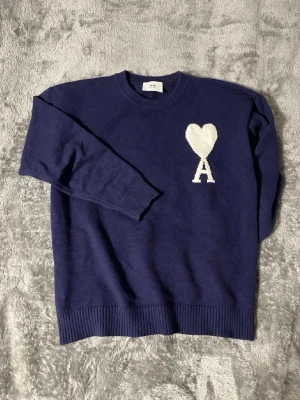 Mörkblå stickad tröja Ami Paris - Snygg tröja med ett A tryck på bröstet, varm å skön till vintern! Den är i storlek M och är i mycket fint skick, mer eller mindre aldrig använd. Skriv vid eventuella frågor!