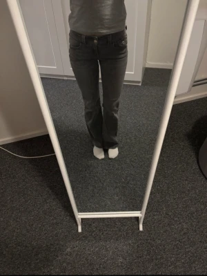 Grå bootcut jeans  - Snygga grå lågmidjade jeans med bootcut-snitt. Klassisk femficksmodell med bälteshällor och dragkedja. .