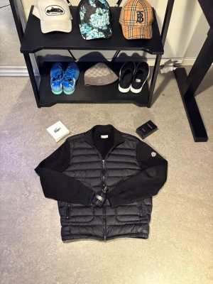 Svart vindjacka från Moncler - Snygg svart vindjacka från Moncler med quiltad front och ärmar i mjukare material. Jackan har dragkedja framtill, ståkrage och Moncler-logga på ärmen. Perfekt för dig som vill ha en stilren och sportig look. Kvitto finns digitalt.