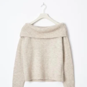 Beige offshoulder stickad tröja - Supermjuk och mysig beige stickad tröja med bred ribbad offshoulder-krage. Perfekt för lager på lager och chill höst- eller vinterstil. Långärmad och loose fit för en avslappnad vibe.