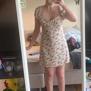 Blommig kortklänning🌹 - Blommig kortklänning!🌹  Klänningen har puffärmar, snörning framtill och en lätt urringning. Materialet känns som tunn polyester, perfekt för varma dagar. Snygg öppen rygg och figurnära passform. OBS: Från SHEIN(några år gammal), men kvaliteten känns okej!