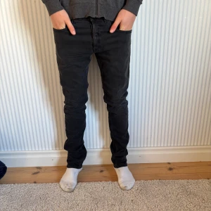 Svarta Replay jeans, storlek 30 - Säljer ett par svarta jeans från Replay i storlek 30. Jeansen har en slim passform med raka ben och klassisk femficksdesign. Snygg, mörk tvätt och diskreta detaljer. Perfekta för dig som gillar stilrena och bekväma jeans. Storlek:30. Pris kan diskuteras men just nu: 449kr!