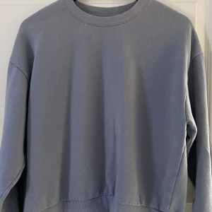 Ljusgrå sweatshirt från H&M - Enkel och stilren ljusgrå sweatshirt från H&M i storlek S. Tröjan har rund halsringning, långa ärmar och ribbade muddar vid hals, ärmslut och nederkant. Perfekt för en chill och avslappnad look.