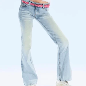 Ljusblå bootcut jeans med rosa bälte - Snygga ljusblå jeans med bootcut-modell och låg midja. Jeansen har klassisk femficksdesign och levereras med ett rosa bälte som ger en extra poppig touch. Perfekta för dig som gillar en avslappnad men trendig stil. Fint skick förutom att dem är slitna längst ner vid hälen.