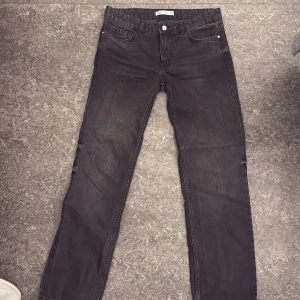 Svarta straight jeans från Zara - Snygga svarta jeans från Zara med klassisk femficksdesign och raka ben. Jeansen har en mörk tvätt och silverfärgad knapp framtill. Passar dig som gillar enkel och stilren look. Materialet är jeans och modellen är straight low waist.