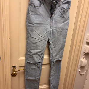Levi's High Rise Skinny jeans ljusblå - Ljusblå Levi's High Rise Skinny jeans i storlek 30 men skulle säga att de är mer som en 28. med slitna knän och slitet på baksida lår. Hög midja och smal passform som sitter snyggt längs benen. Jeansen har den ikoniska Levi's-lappen och röd etikett bak. Hålen har jag gjort själv.
