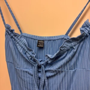 Blå ribbad klänning från SHEIN - Supersöt blå klänning från SHEIN i storlek S med smala axelband och ribbat tyg. Klänningen har knytning framtill. Stretchig och skön.