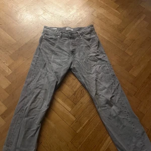 Grå jeans från Jack & Jones, 29/30 - Snygga grå jeans från Jack & Jones med klassisk femficksdesign och raka ben. Jeansen har normal passform och är tillverkade i mjukt jeanstyg. Perfekt för dig som gillar en enkel och stilren look.