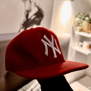 Röd New Era keps - Snygg röd keps från New York Yankees med klassisk vit broderad NY-logga framtill. Kepsen har rak skärm, STRL justerbar men klassiska ”knappar” som finns på mer eller mindre alla kepsar. Kepsen är tillverkad i ett mjukt tyg som ger en schysst look och perfekt för dig oavsett kön, stil eller ålder. Köpt på Hatstore för 599kr och hade i princip kunna sålt den för samma pris med tanke på att den är helt ny lägger ut den billigare nu! Skriv privat vid minsta fundering. :) 