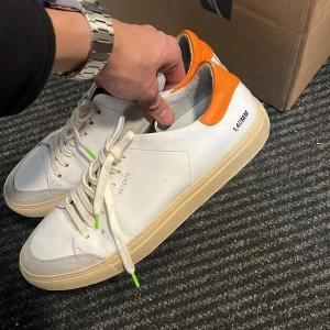 Axel Arigato vita sneakers med orange detalj - Helt okej skick, storlek 45