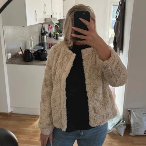 Ljusbeige ”pälsjacka” - En ljusbeige ”pälsjacka” i strl M från Vero Moda. (Knappar för att stänga jacka). Mycket bra skick!