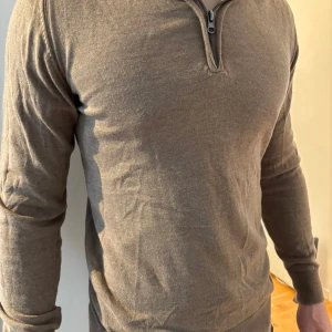 Beige half zip tröja från Indicode - Säljer en brun/beige långärmad tröja från Indicode i storlek small. Tröjan har en snygg half zip-dragkedja vid halsen och är tillverkad i mjukt material. Perfekt för lager-på-lager och chill stil.