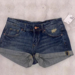 Blå jeansshorts från H&M, strl 36 - Snygga blå jeansshorts från H&M. Provat den en gång, har aldrig haft på den. Perfekta för varma dagar och har en cool, avslappnad vibe.