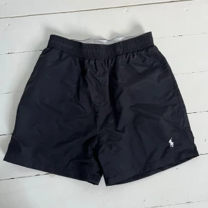 Svarta badshorts från Polo Ralph Lauren - Svarta badshorts från Polo Ralph Lauren med elastisk midja och innerfoder i mesh. Klassisk design med broderad logga framtill och en bakficka med lock. Perfekta för stranden eller poolen. Självklart äkta som alla andra varor på min sida🤩🤩