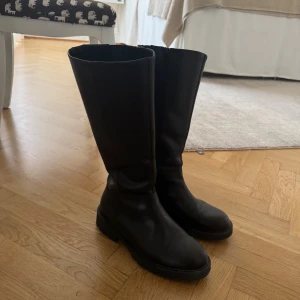 Svarta höga boots med dragkedja - Säljer ett par svarta höga boots i skinn med  grov sula och dragkedja baktill. 