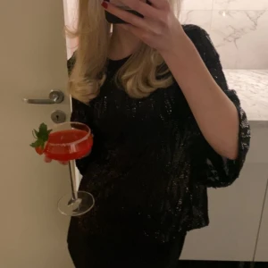 Svart paljettblus från Zara - Säljer en svart blus från Zara med glittriga paljetter och mönstrad yta. Blusen har rund hals, vida trekvartsärmar och är croppad i modellen. Perfekt för att sticka ut med lite extra glam. 