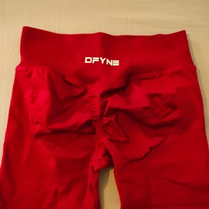 Röda DFYNE shorts med scrunch - Snygga röda shorts från DFYNE med hög midja och scrunch-detalj bak för extra shaping. Stretchigt material som sitter tight och bekvämt, perfekt för gymmet eller andra träningspass. Logga framtill i vitt.